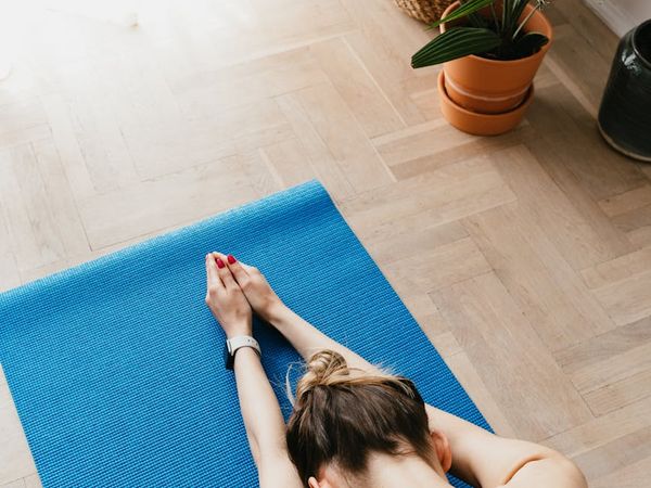 A quiet, minimalist room corner with a yoga mat and a plant.